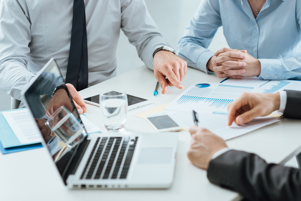 Professional business team working together at office desk discussing during a meeting, efficiency and teamwork concept